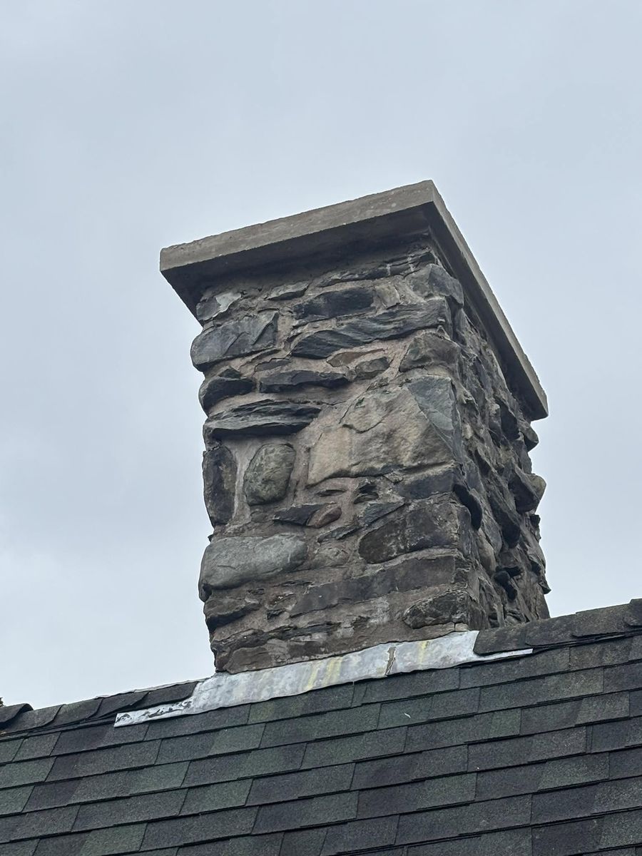 Stone chimney rebuilt with a heavy cut cap slab and new flashing