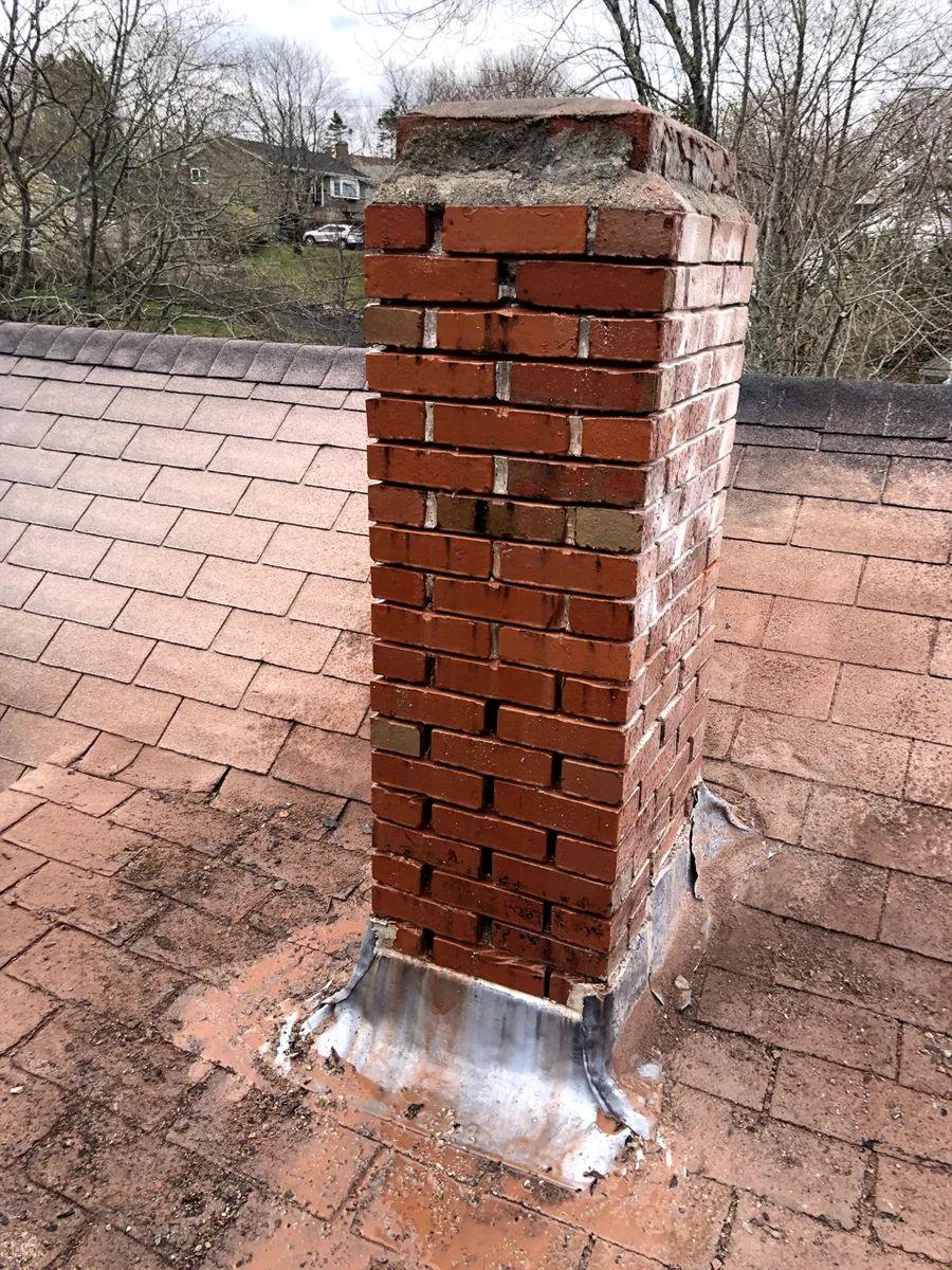 Red brick chimney freshly repointed with new flashing at the roof line